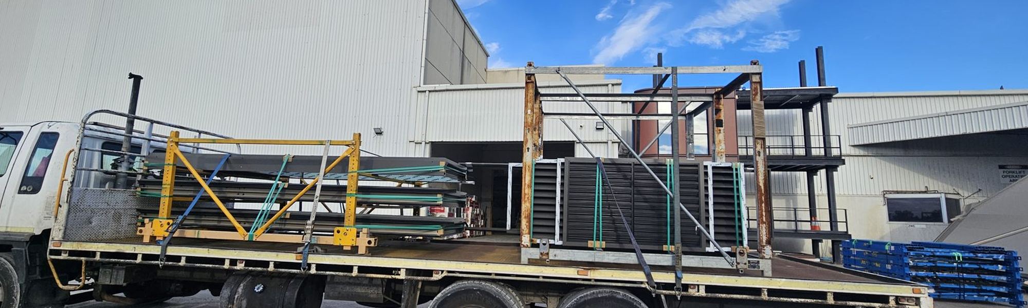 A TLH truck loaded with galvanised steel frames pulling out of the yard.