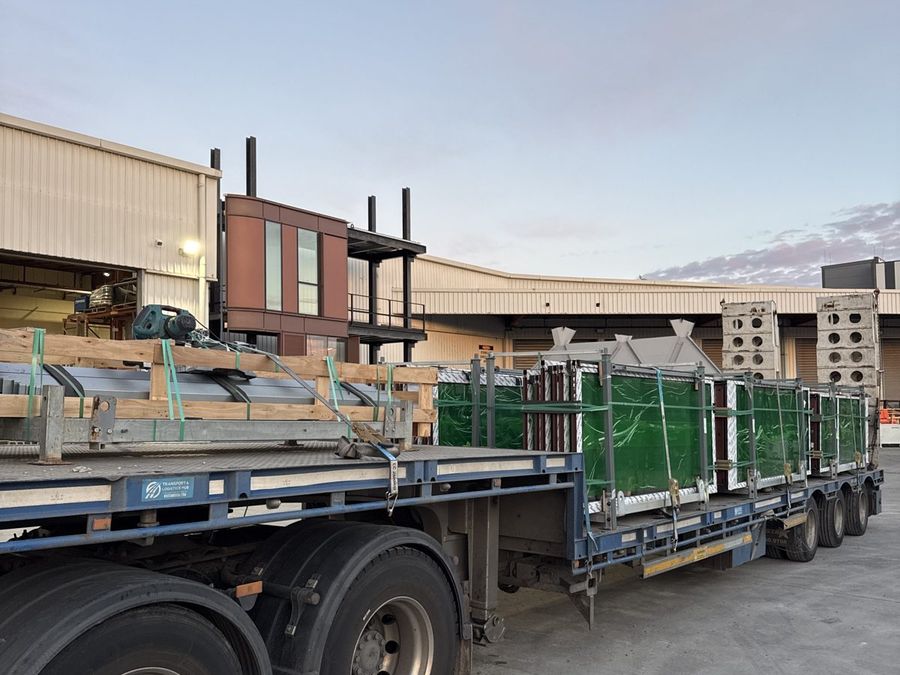 Loaded TLH trailer at dawn, steel and glazing strapped down outside the yard.